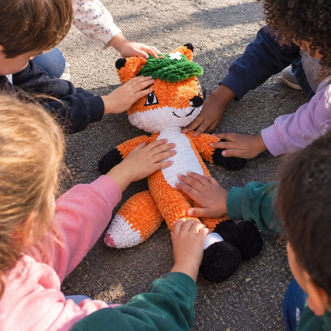 Des enfants autour de Rescue le Renard dans une cour d'école